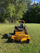 front view of a cub cadet zero turn on a green lawn with trees in the background